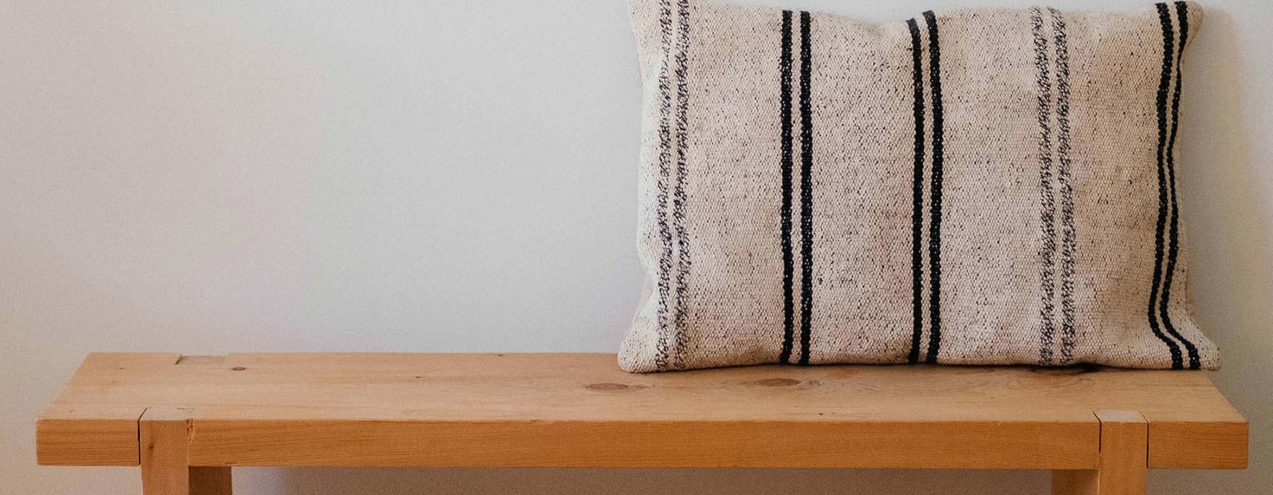 a wooden bench with a striped pillow on it